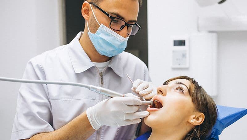 https:Dentist examining a female patient’s teeth during a check-up, representing the connection between nutrition, oral health, and preventive dental care at South Gate Smile Dental in South Gate, CA.